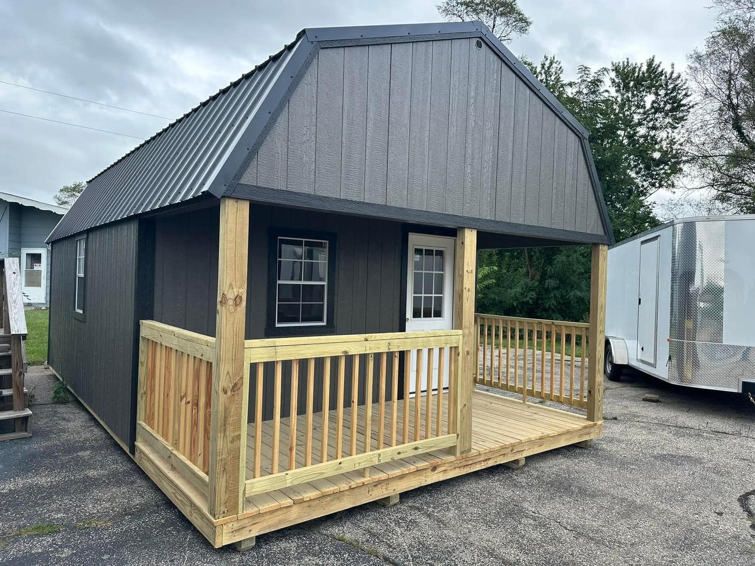 Gray gambrel-roof cabin with a wraparound wooden porch