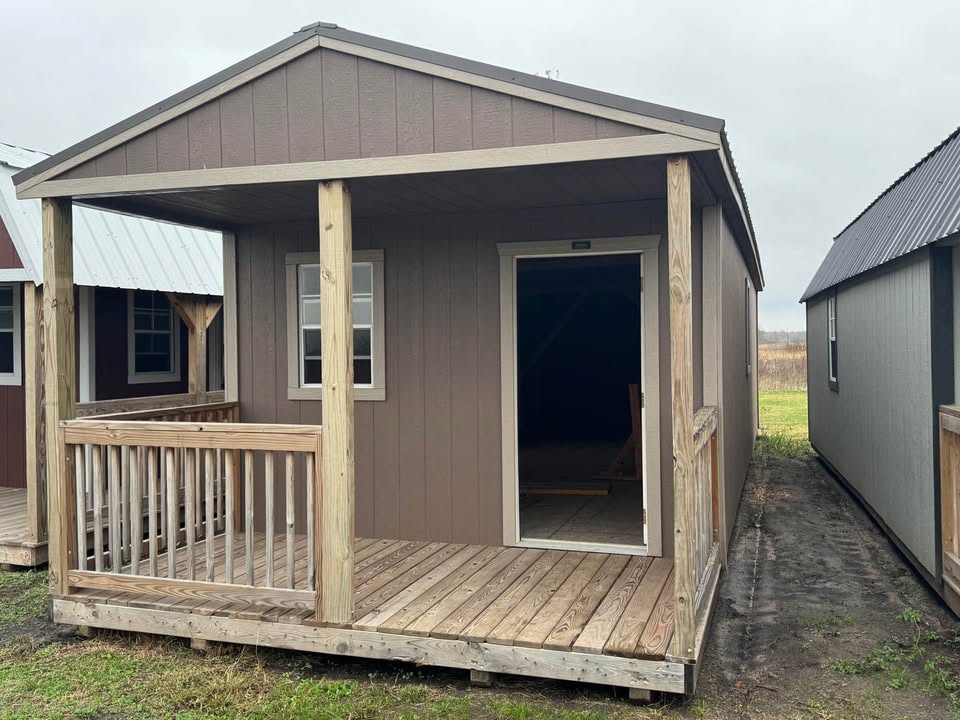 Tan cabin shell with a wooden front porch and railing