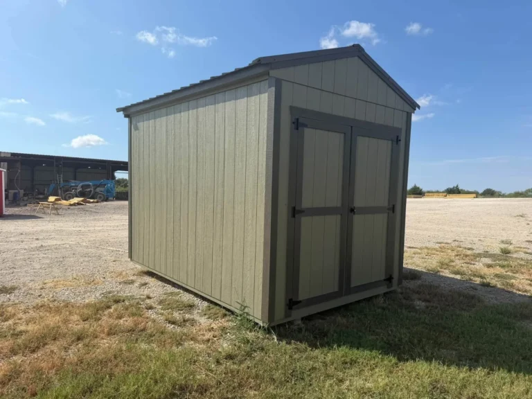 Khaki utility shed with dark brown trim and double doors, seen from the side on the sales lot