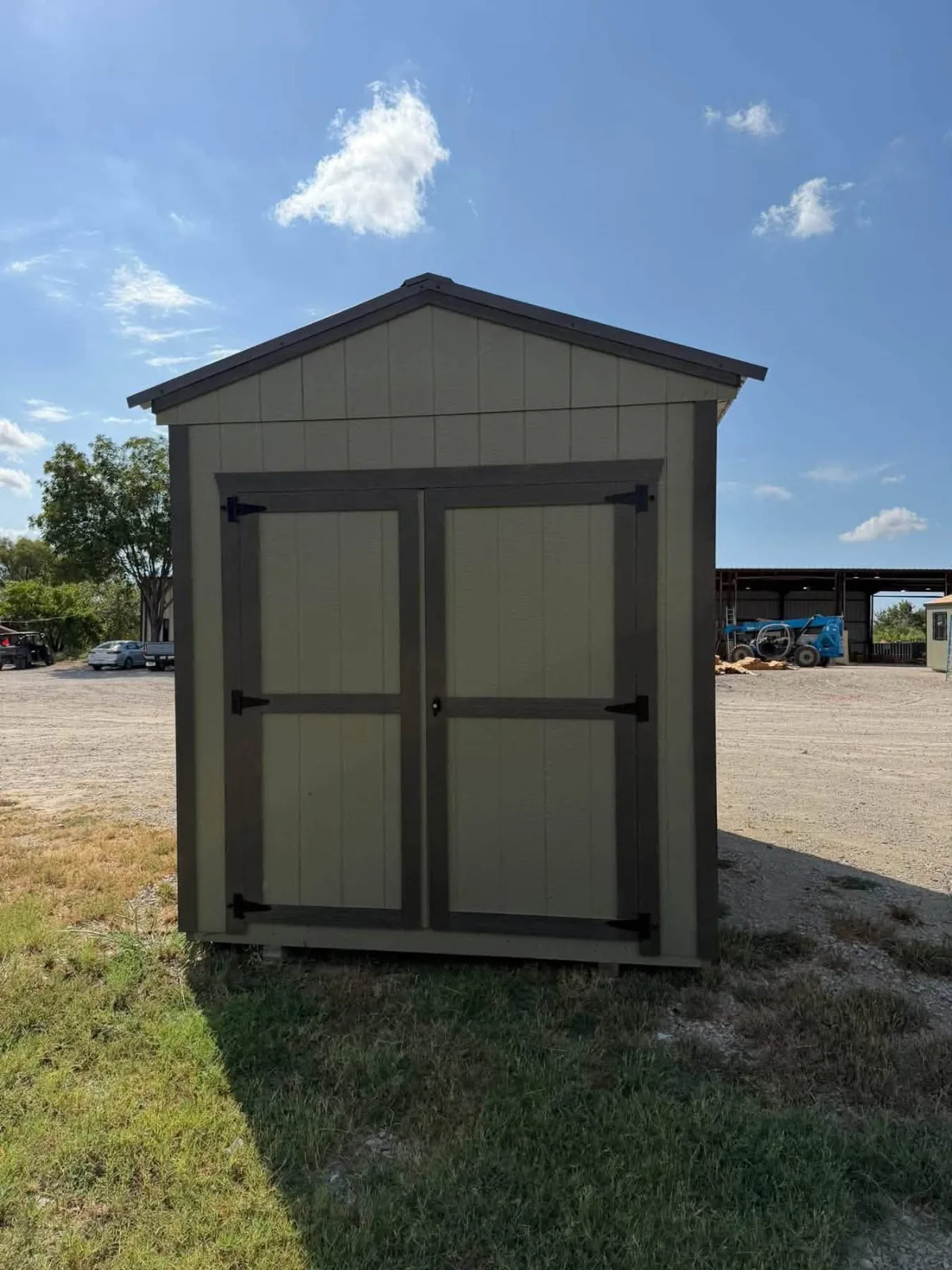 Front of a khaki utility shed with dark brown trim and wide double doors under a gable roof