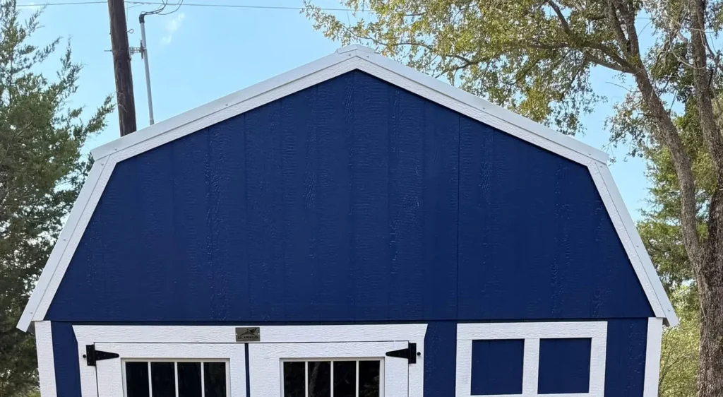 Navy blue 12x20 lofted barn with white trim, a gambrel roof, double doors with transom windows, and a white-framed window, delivered near Corsicana