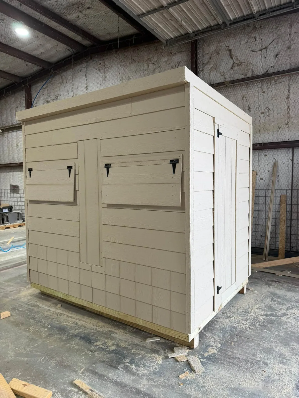 Tan utility shed with lap siding, double doors, and a single side door, finished inside the build shop